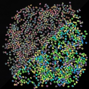 Macro detail of colorful 2mm AB glass seed beads on black background for DIY crafts