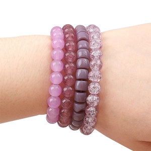 Set of four purple crystal bead bracelets with diverse textures worn on wrist