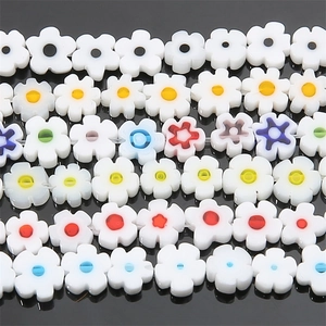 Flat lay of multi-colored floral resin beads with white petals for DIY jewelry making