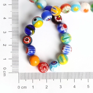 Macro shot of colorful millefiori glass beads showing floral patterns on a scale ruler