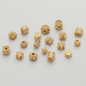 Detailed macro of gold-plated copper beads including flower, clover, and Fu character shapes