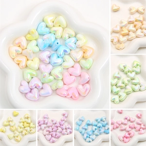 Macro view of iridescent acrylic heart beads in assorted pastel macaron colors for DIY crafts