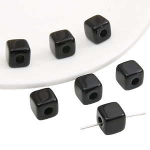 Macro shot of black acrylic cube beads with hole detail for DIY jewelry making