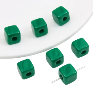 Close-up of glossy green acrylic cube beads with pre-drilled holes for DIY jewelry making