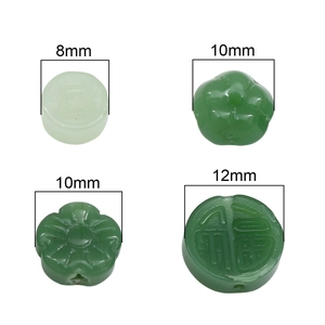 Macro view of green glass faux jade beads in flower, coin, and Fu character shapes