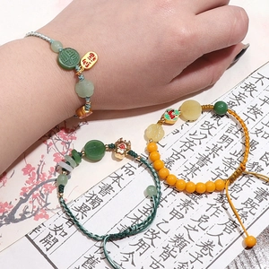 Detail of handmade woven bracelets with jade-like beads and Chinese fortune charms