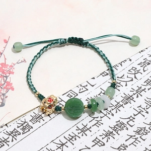 Detailed view of woven green bracelet with Pixiu charm and Fu character jade bead