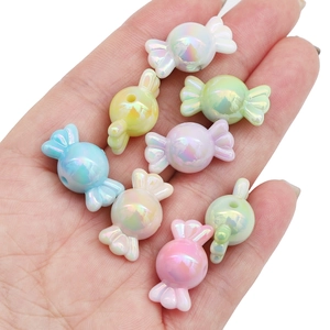 Gros plan de perles en acrylique irisées en forme de bonbon tenues dans une main