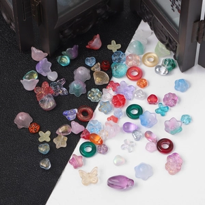 Detailopname van gekleurde glazen kralen in vlinder- en bloemvorm voor DIY-sieraden