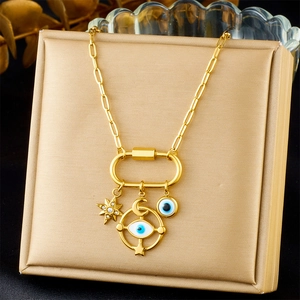 Détail d'un collier plaqué or avec breloques étoile et œil protecteur sur une chaîne à maillons