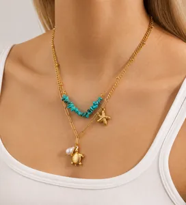 Détail d'un collier doré à deux rangs avec pendentifs étoile de mer et tortue