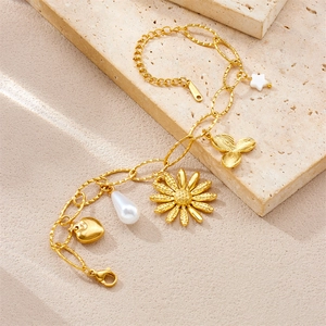 Detail of gold-plated stainless steel charm bracelet with heart, pearl and flower pendants