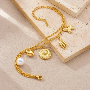 Detail of gold-plated double-layer bracelet with pearl, heart, and butterfly charms
