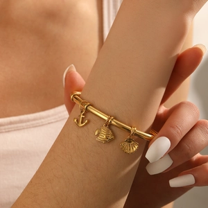 Gold stainless steel bangle with nautical charms including anchor, fish and shell