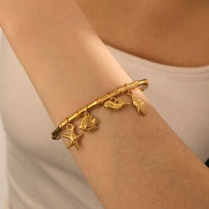 Detail of gold-plated bamboo-style bangle with starfish and whale marine charms