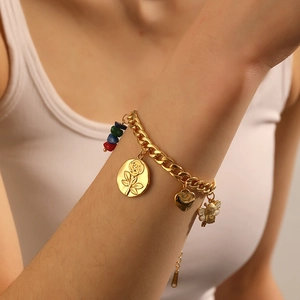 Detail of gold chain bracelet with rose medallion, bee charm and colorful stones