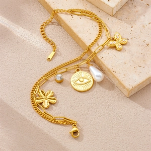Detailed close-up of double-layer gold plated bracelet with butterfly and pearl charms