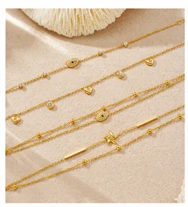 Dettaglio di bracciali placcati in oro con ciondoli a occhio e stella su sfondo sabbia