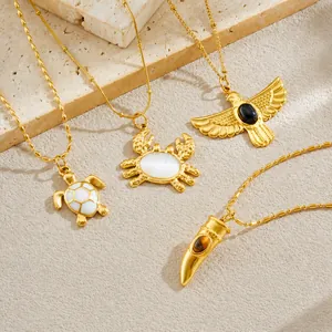 Detalle de collares bañados en oro con colgantes de tortuga y cangrejo sobre piedras