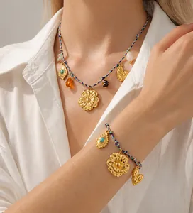 Détail de pendentifs bohèmes en forme de fleur et cœur sur collier tressé