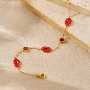Vue détaillée d'un bracelet doré avec des breloques lèvres rouges et cœurs en zircon