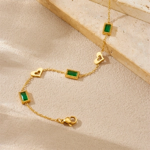 Détails d'un collier vintage doré avec pierres émeraude et breloques en forme de cœur