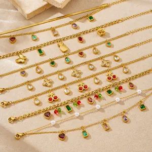 Detail van vergulde armbanden met kleurrijke zirkonia kers- en ananashangers