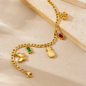 Detail van vergulde armband met hangers in de vorm van kers, ananas en vlinder
