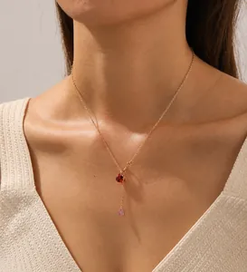 Primo piano della catena in acciaio dorato con un delicato ciondolo a cuore in rubino rosso