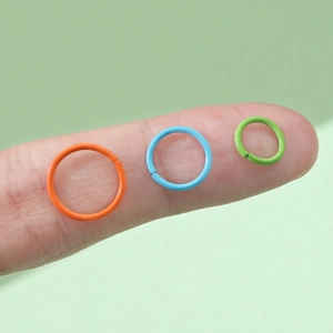 Anellini aperti colorati da 8-12mm per fai-da-te mostrati sulla punta di un dito