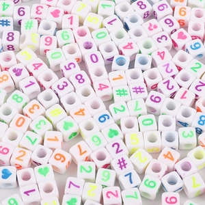 Macro shot of white acrylic square beads with colorful numbers and heart patterns for DIY
