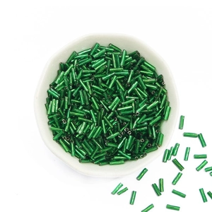 Green bugle beads in a white bowl for DIY jewelry making and embroidery crafts