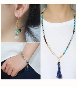 Dettaglio di set gioielli boho con turchese, occhio di tigre, nappe e catena dorata