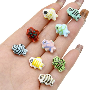 Handheld display of colorful hand-painted ceramic fish beads for DIY jewelry making