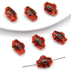 Macro detail of hand-painted orange fish ceramic beads with pre-drilled holes for DIY