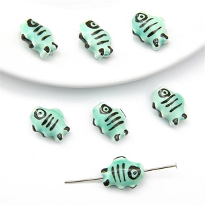 Close-up of mint green hand-painted ceramic bee-shaped beads for DIY jewelry making