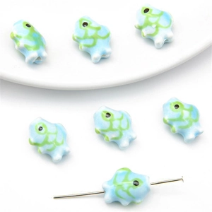 Macro detail of hand-painted turtle ceramic beads with holes for DIY jewelry making