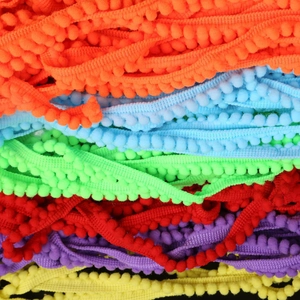 Close-up of vibrant 10mm multi-colored pom-pom fringe trim for sewing and DIY crafts