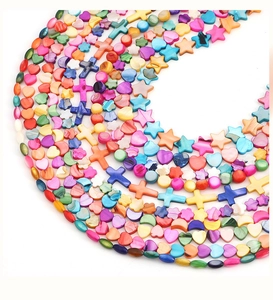 Macro view of colorful natural shell beads in heart, star, and moon shapes for DIY jewelry