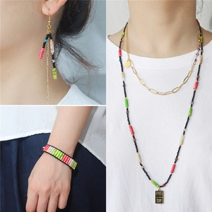 Detailed shot of ethnic beaded jewelry featuring colorful tube beads and tassel earrings