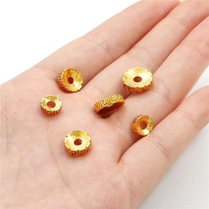 Cuentas espaciadoras doradas DIY con patrón griego mostradas en la mano para escala