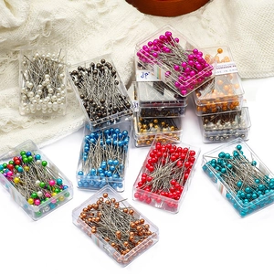 Macro shot of colorful pearl head stainless steel dressmaker pins in small storage cases