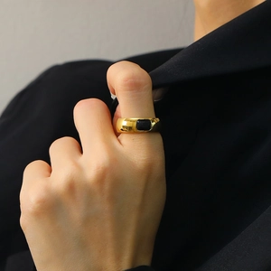 Anillo minimalista de acero dorado con piedra negra cuadrada usado por una modelo