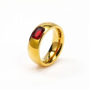 Detalle de un anillo grueso de acero inoxidable dorado con una circonita roja rectangular