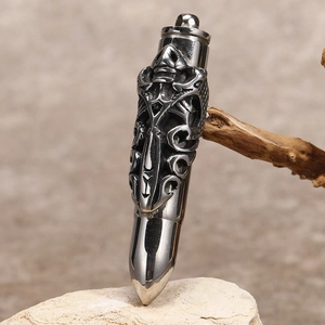 Gothic bullet pendant with dragon relief on white stone and wood background