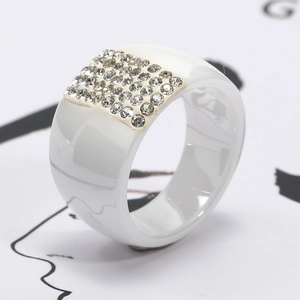 Close-up of a wide white ceramic ring featuring a rectangular grid of sparkling crystals