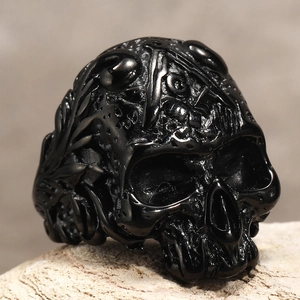 Makrodetail eines Gothic-Totenkopfrings mit schwarzen Reliefelementen auf Stein