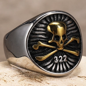 Macro detail of retro punk skull ring with golden 322 crossbones on aged titanium steel