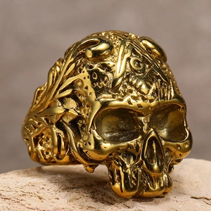 Detailansicht eines goldenen Punk-Totenkopfrings mit kunstvollen Reliefmustern auf Stein