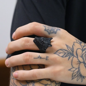 Detailed view of a 3D wolf head punk ring in matte black finish on a tattooed hand